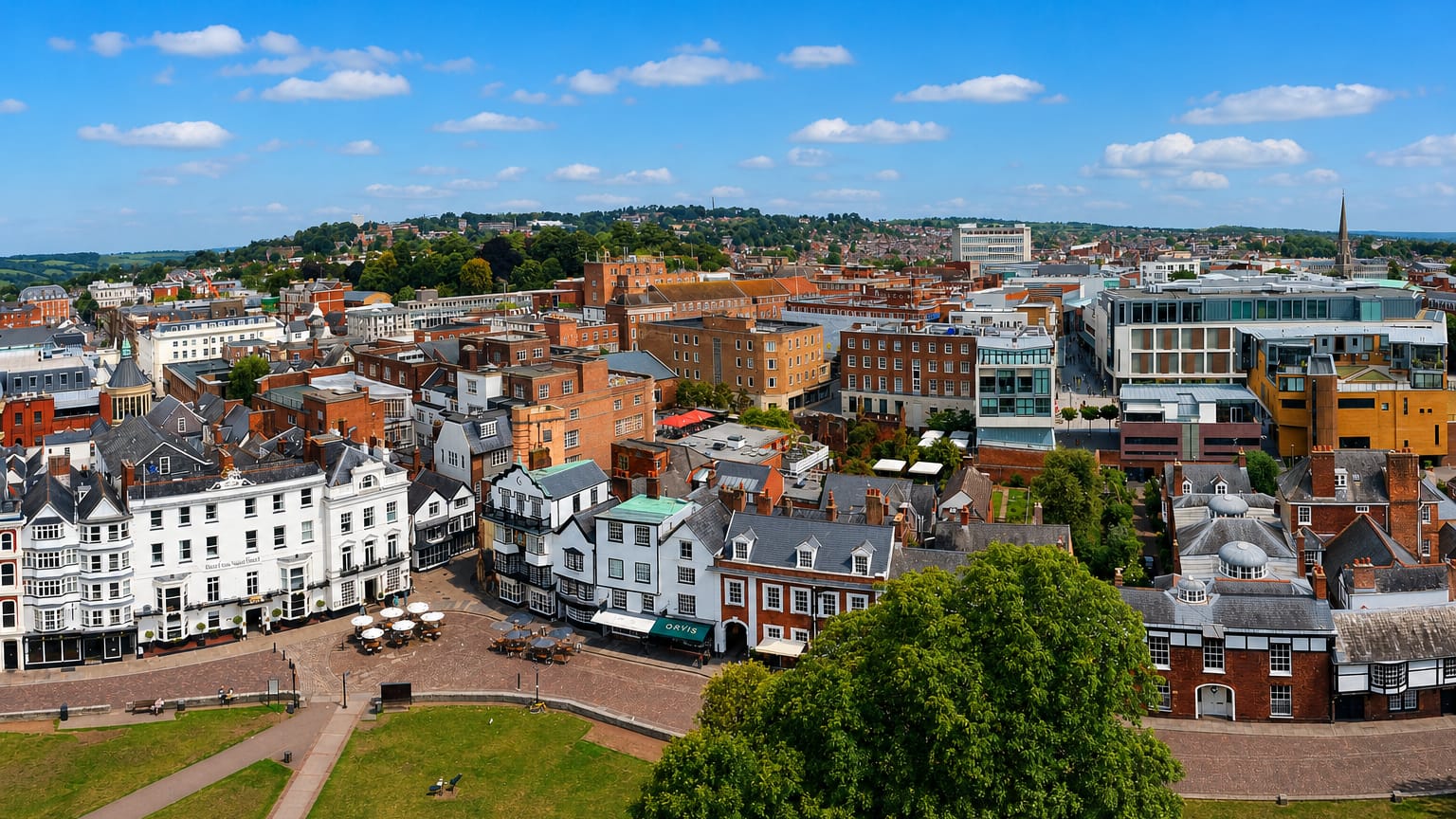 Aerial view over Exeter's historic city centre, with timbered buildings, red-brick terraces and a church spire