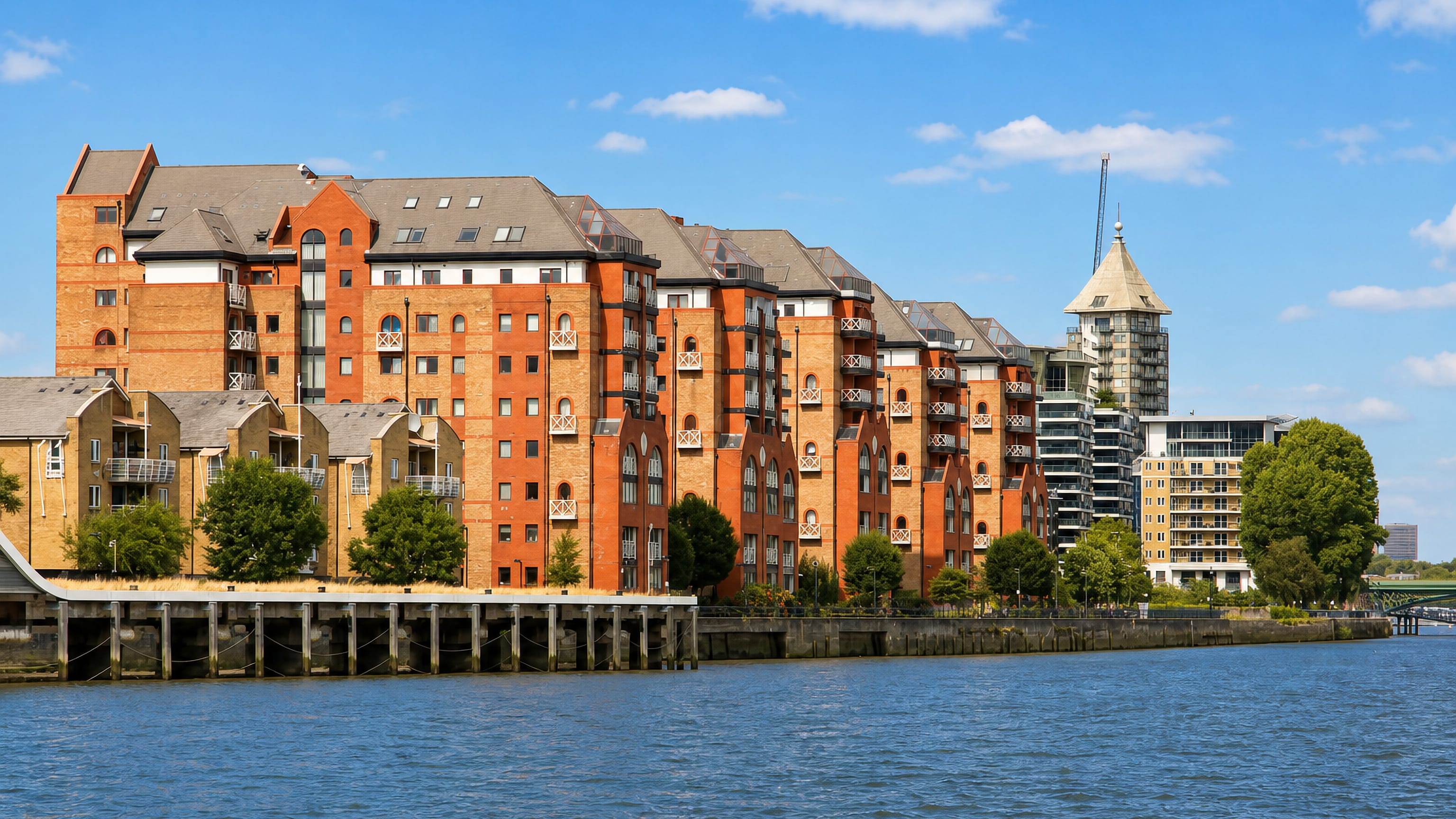 Red-brick riverside apartments along the Thames at Sands End, Fulham, with the Chelsea Harbour tower behind.