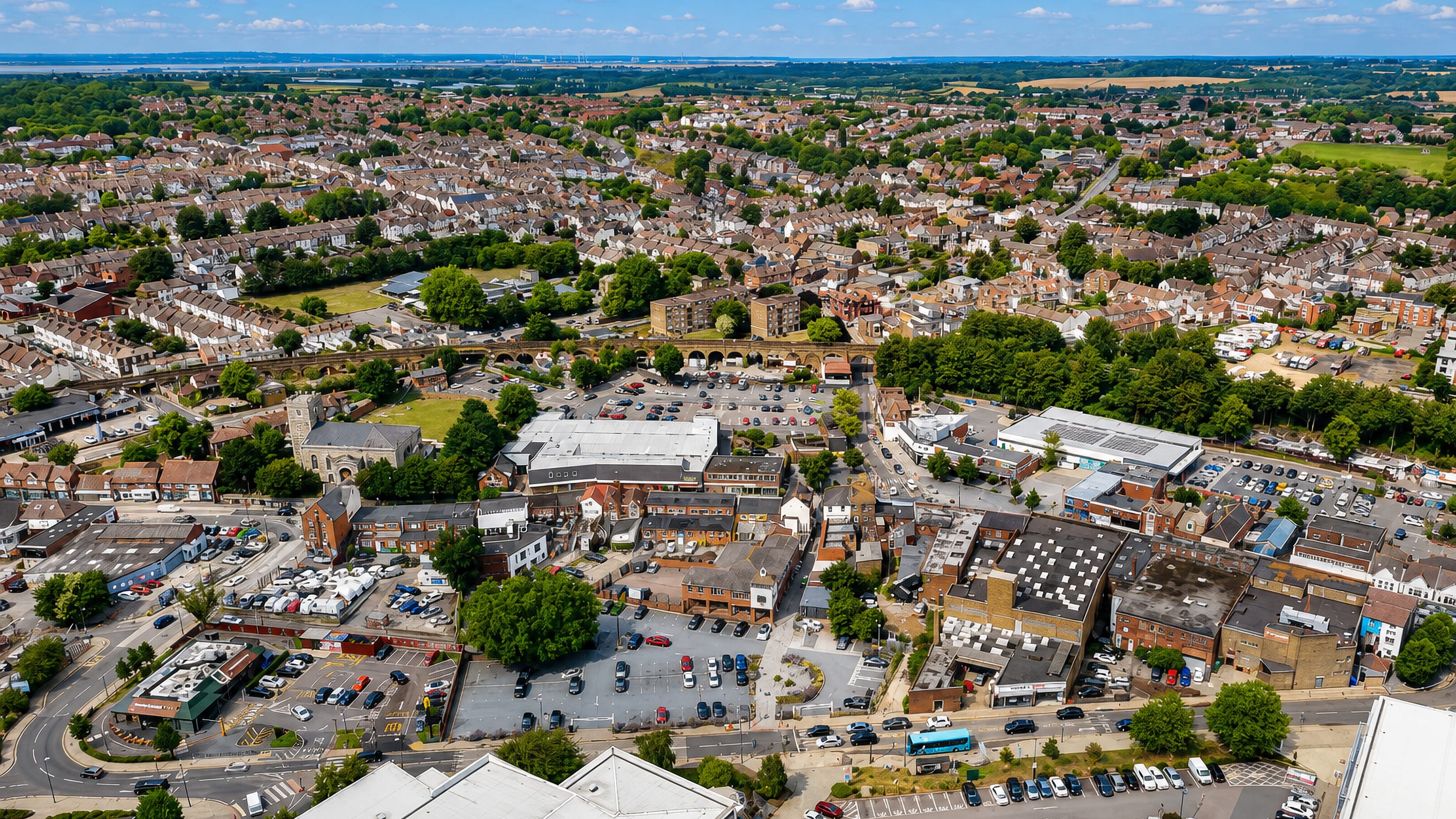 Aerial view of Strood's town centre, terraced streets and rail viaduct with the Medway beyond.
