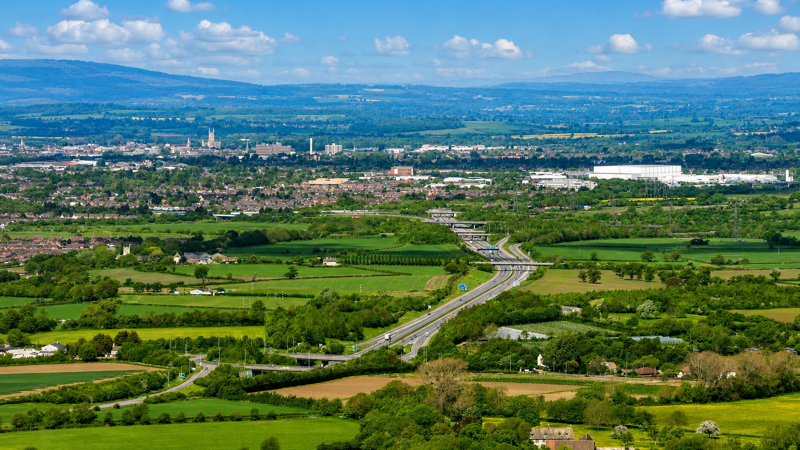 Gloucester spread across the Severn Vale, its cathedral tower on the skyline, seen from the Cotswold escarpment.