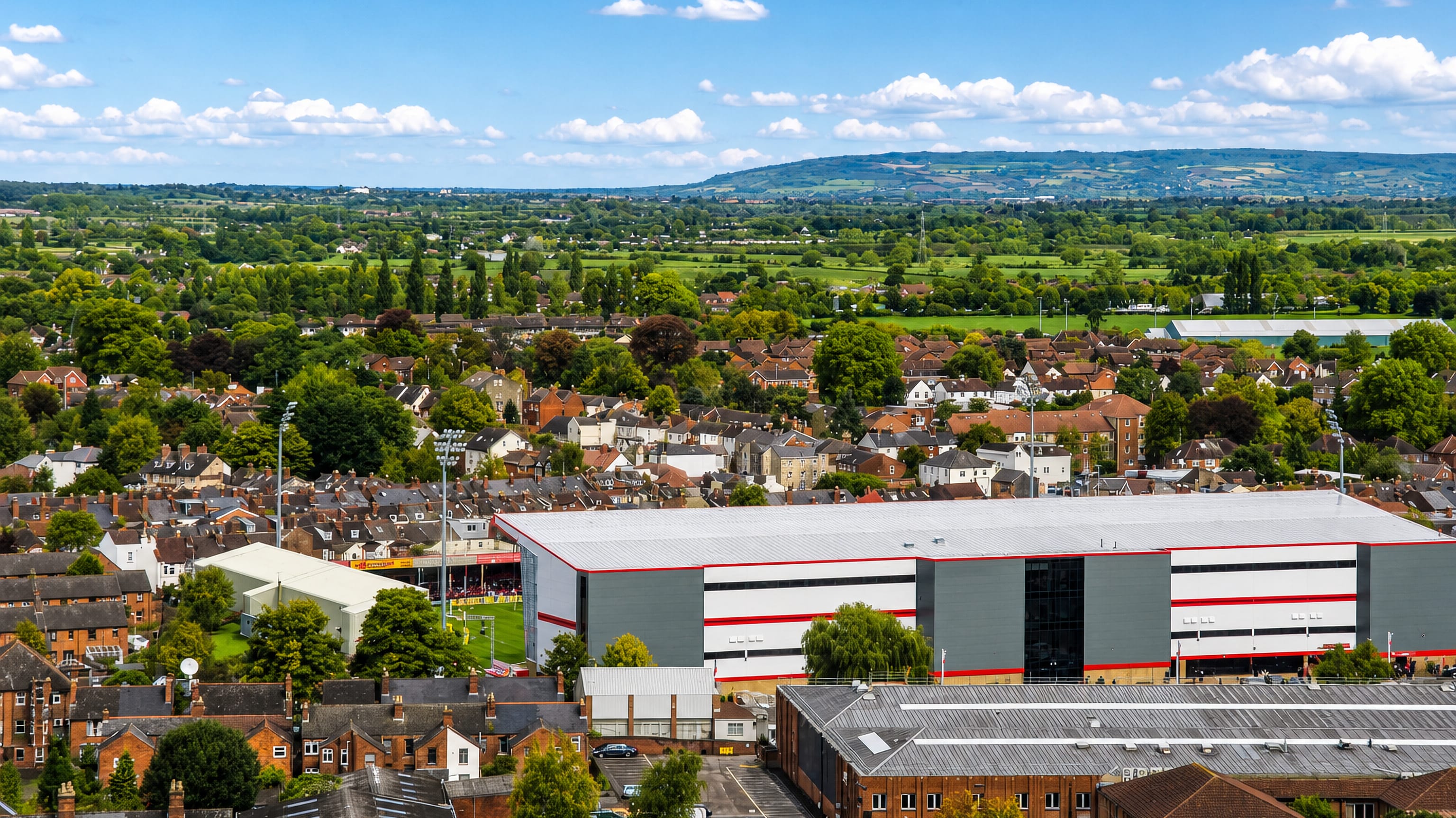 Kingsholm rugby stadium among Victorian terraces in Gloucester, with the Cotswold escarpment on the horizon