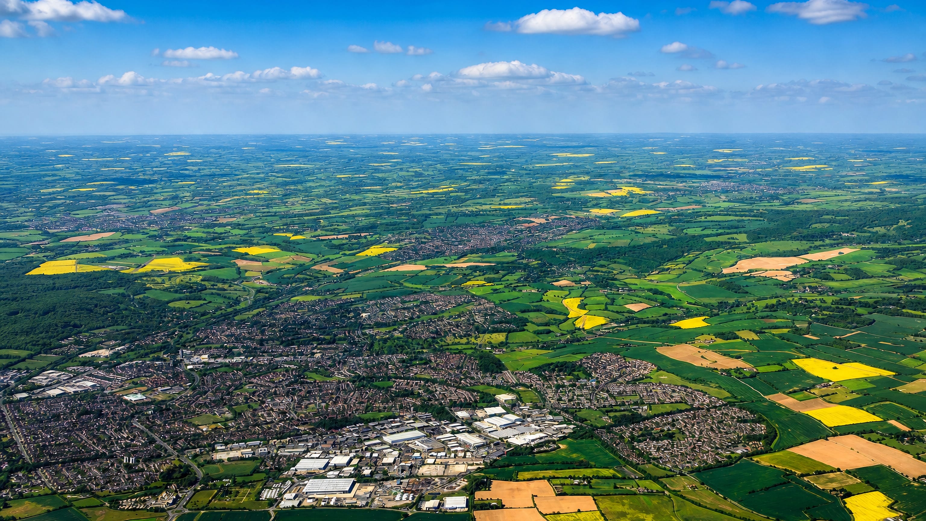High aerial view of Hemel Hempstead spreading through Hertfordshire farmland and rapeseed fields.