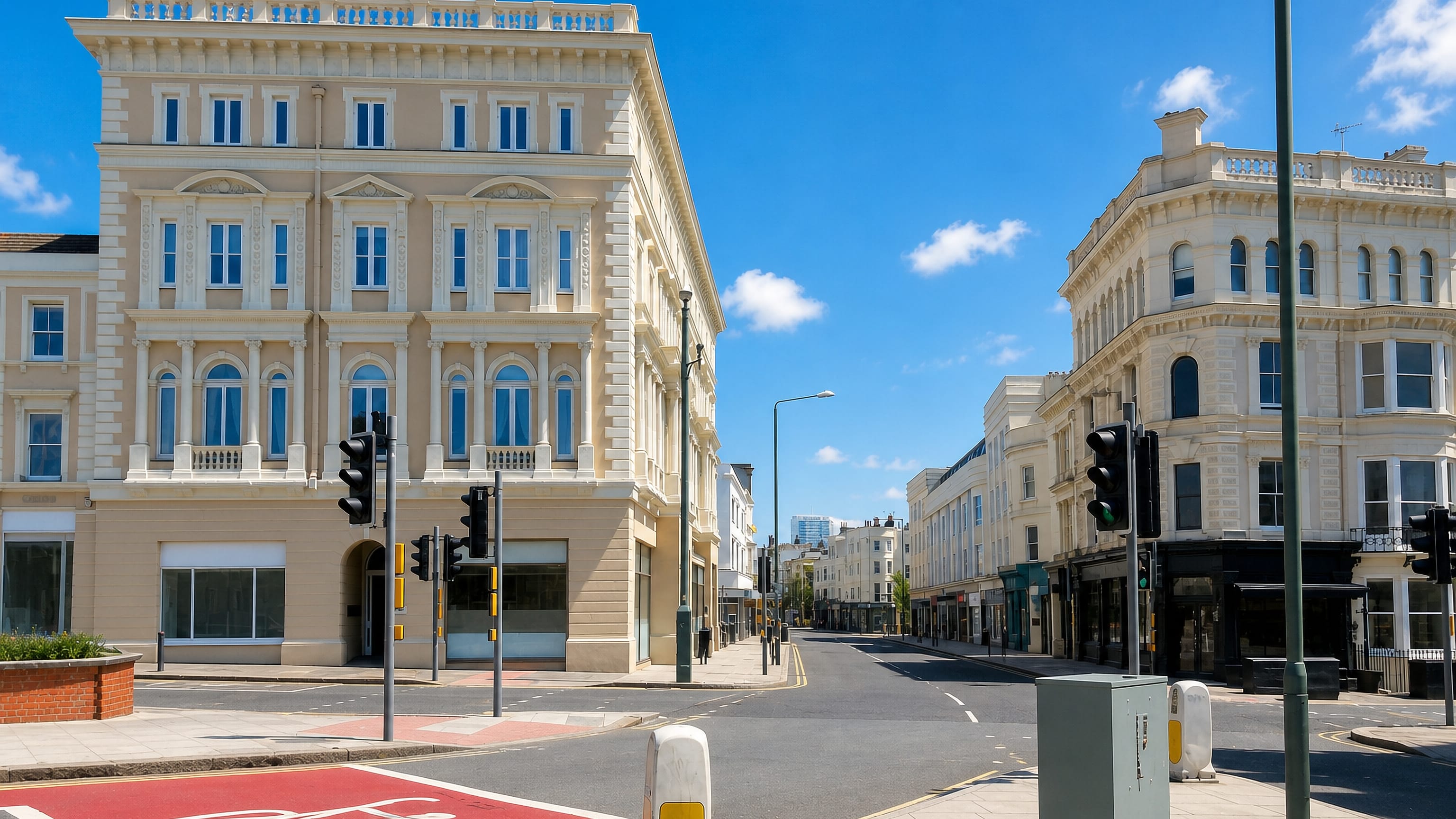 Cream Regency and Victorian corner buildings on a wide street with a red cycle lane in Hove, England.