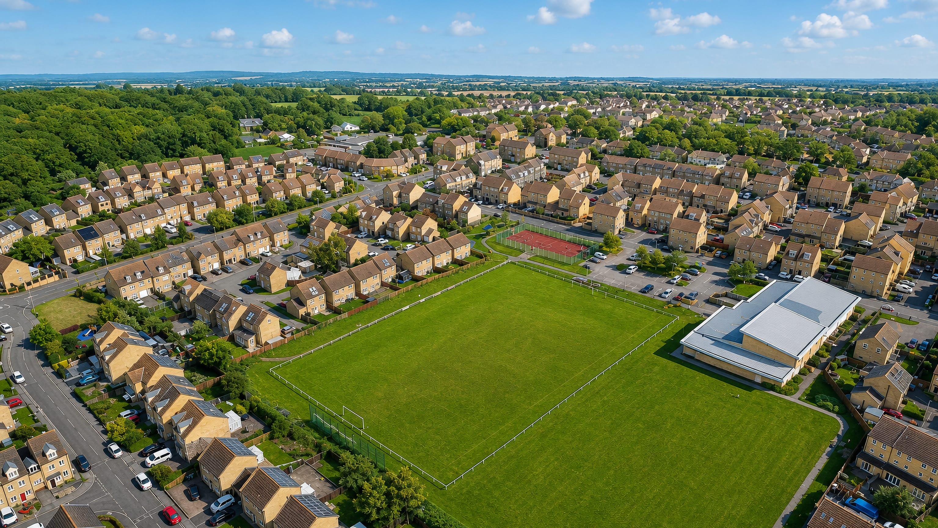 Aerial view of stone-built housing around a playing field in Brackenhall, Huddersfield.