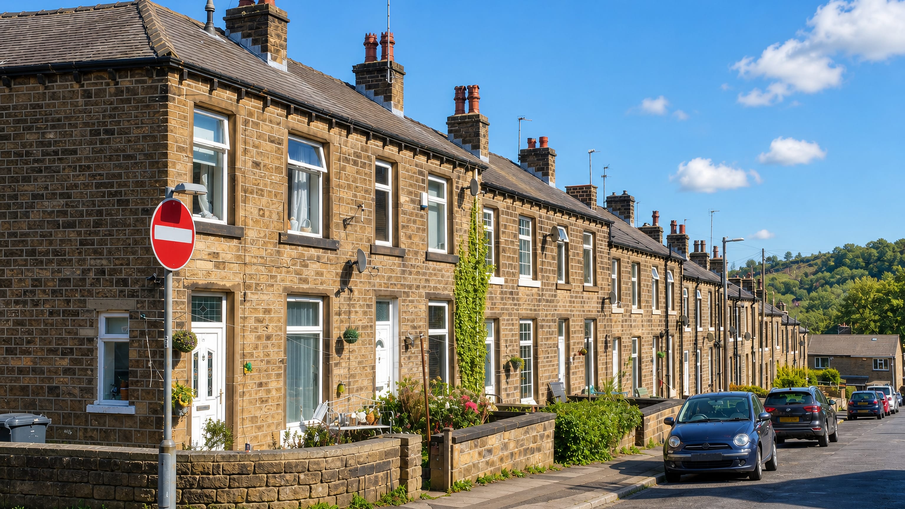 Row of Yorkshire stone terraced houses on a sloping street in Cowlersley, Huddersfield.