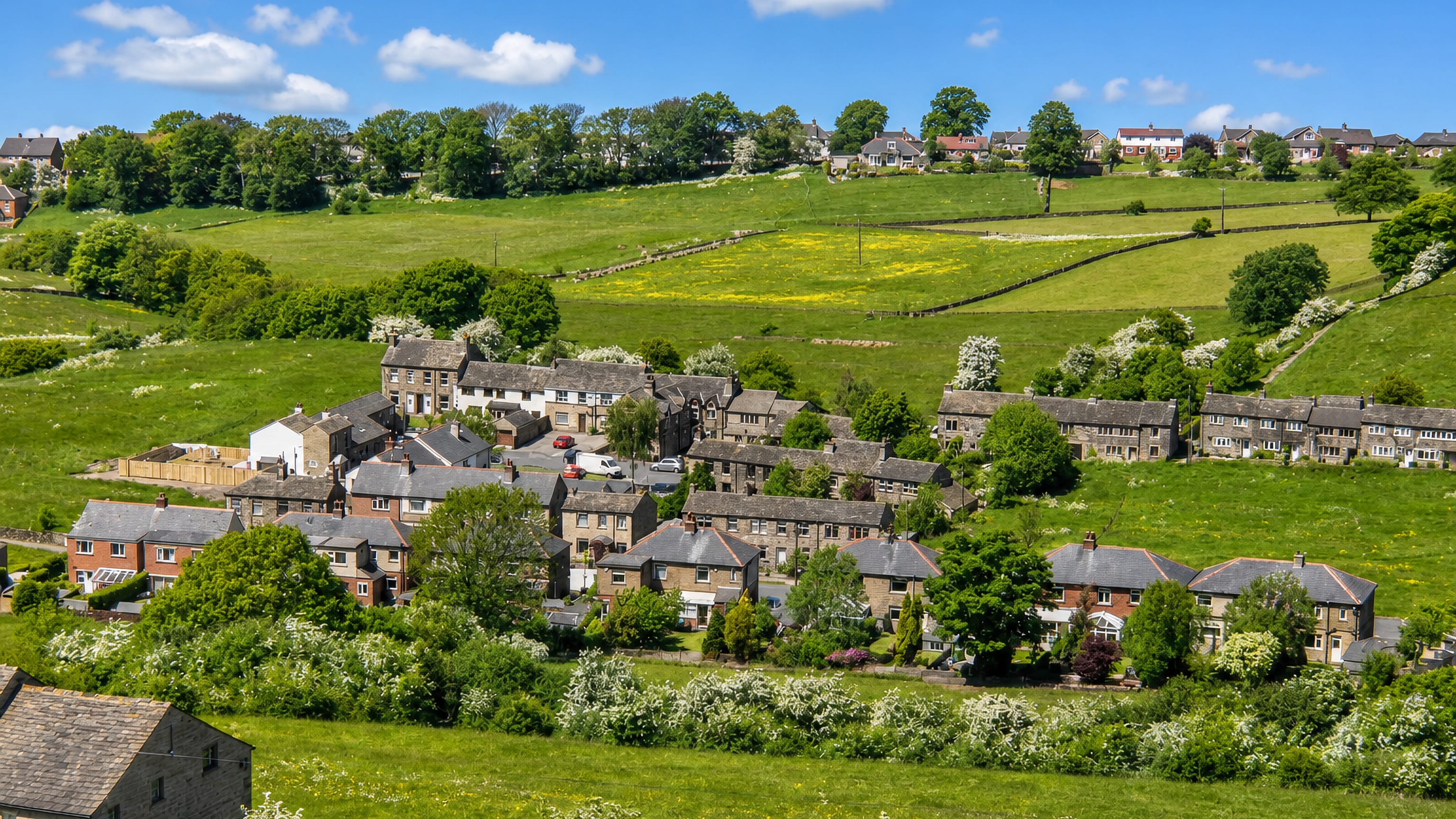 Stone terraces and slate roofs of Hall Bower on a green Pennine hillside above Huddersfield.