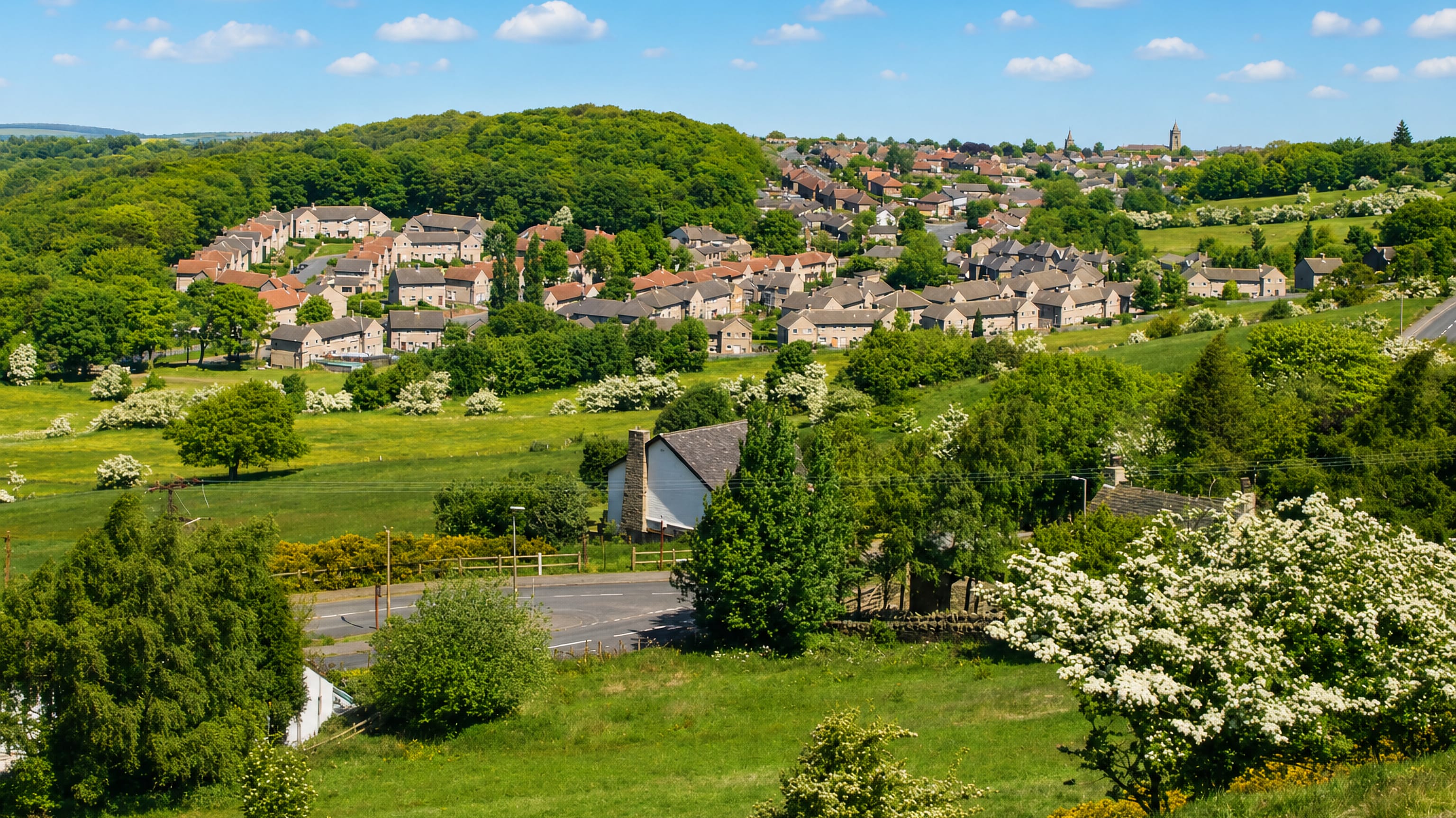 Stone houses of Longley spread across a green hillside above Huddersfield, church spires beyond.