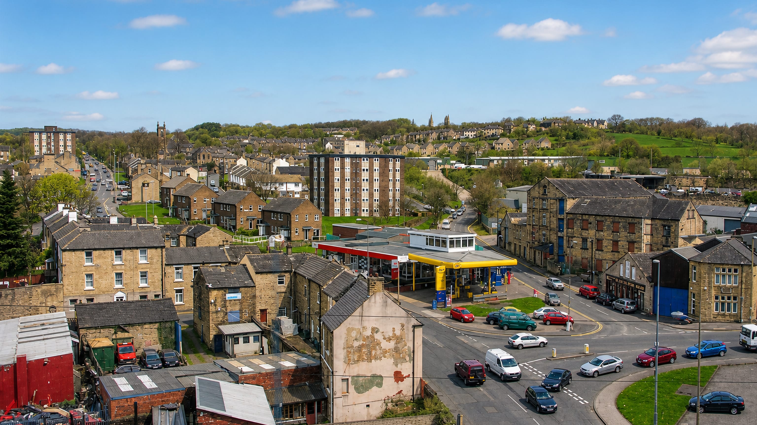 Hillside view over Paddock, Huddersfield, with stone terraces, a mill, tower blocks and a petrol station.