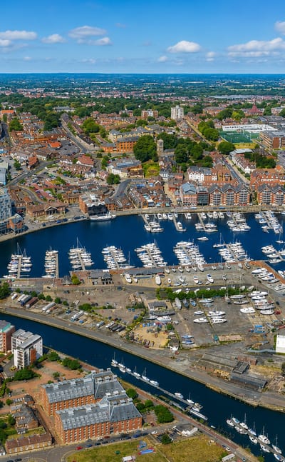 Aerial view of Ipswich Waterfront and its marina full of yachts with the town beyond under a blue sky.
