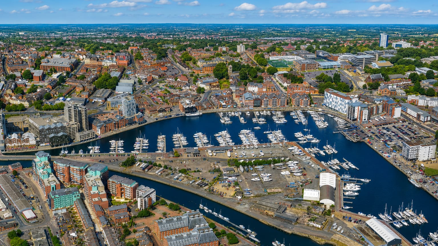 Aerial view of Ipswich Waterfront and its marina full of yachts with the town beyond under a blue sky.