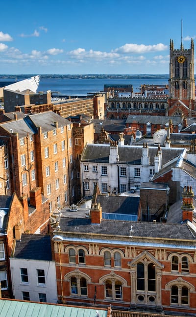 Rooftops of Kingston upon Hull's old town with Hull Minster's tower and the Humber estuary beyond.