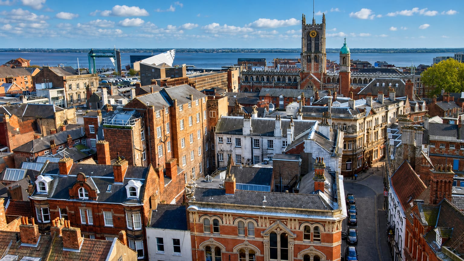 Rooftops of Kingston upon Hull's old town with Hull Minster's tower and the Humber estuary beyond.