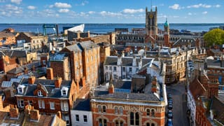 Rooftops of Kingston upon Hull's old town with Hull Minster's tower and the Humber estuary beyond.