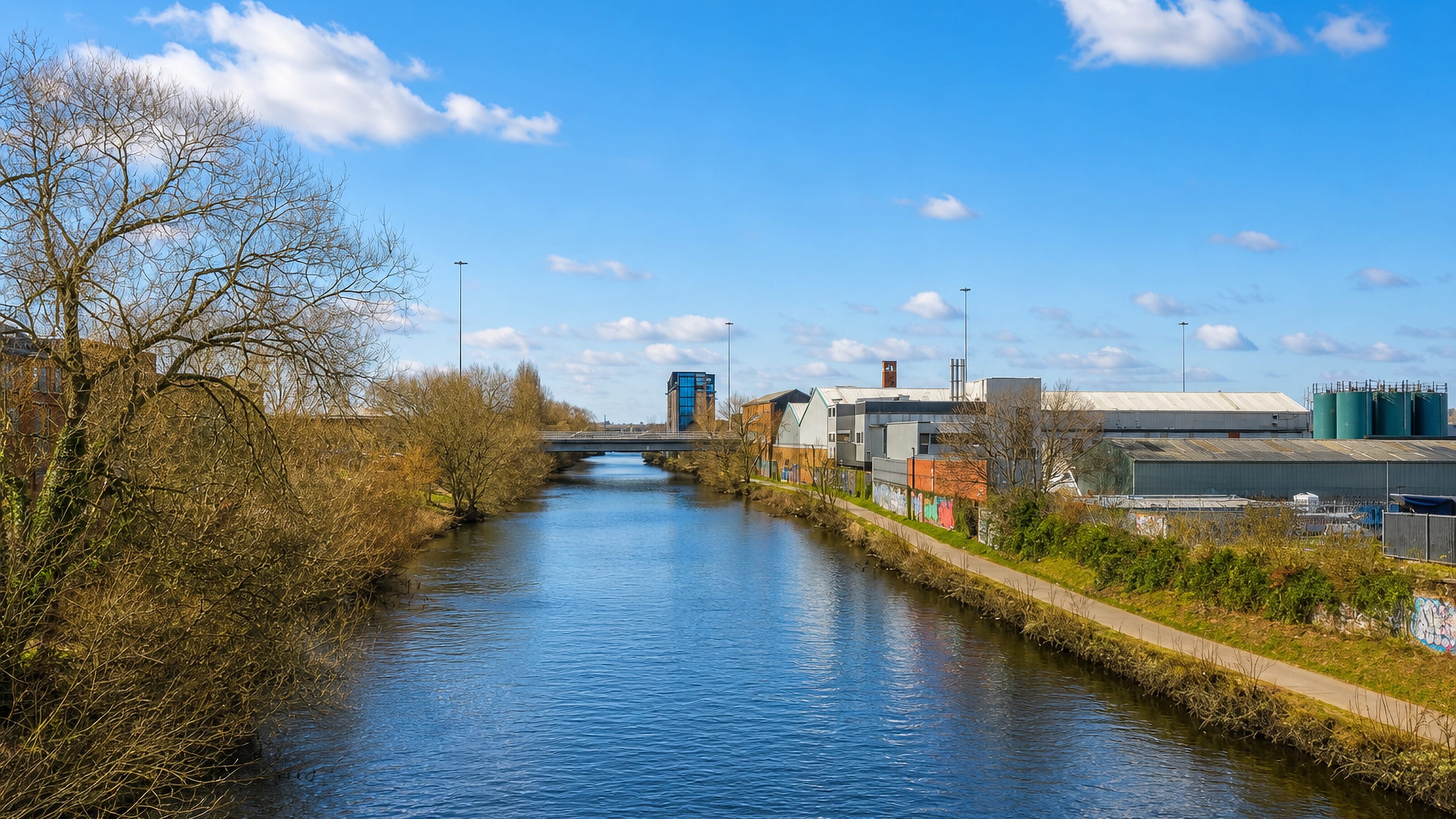River Aire curving past warehouses, silos and a towpath in the Knowsthorpe industrial area of Leeds, England.