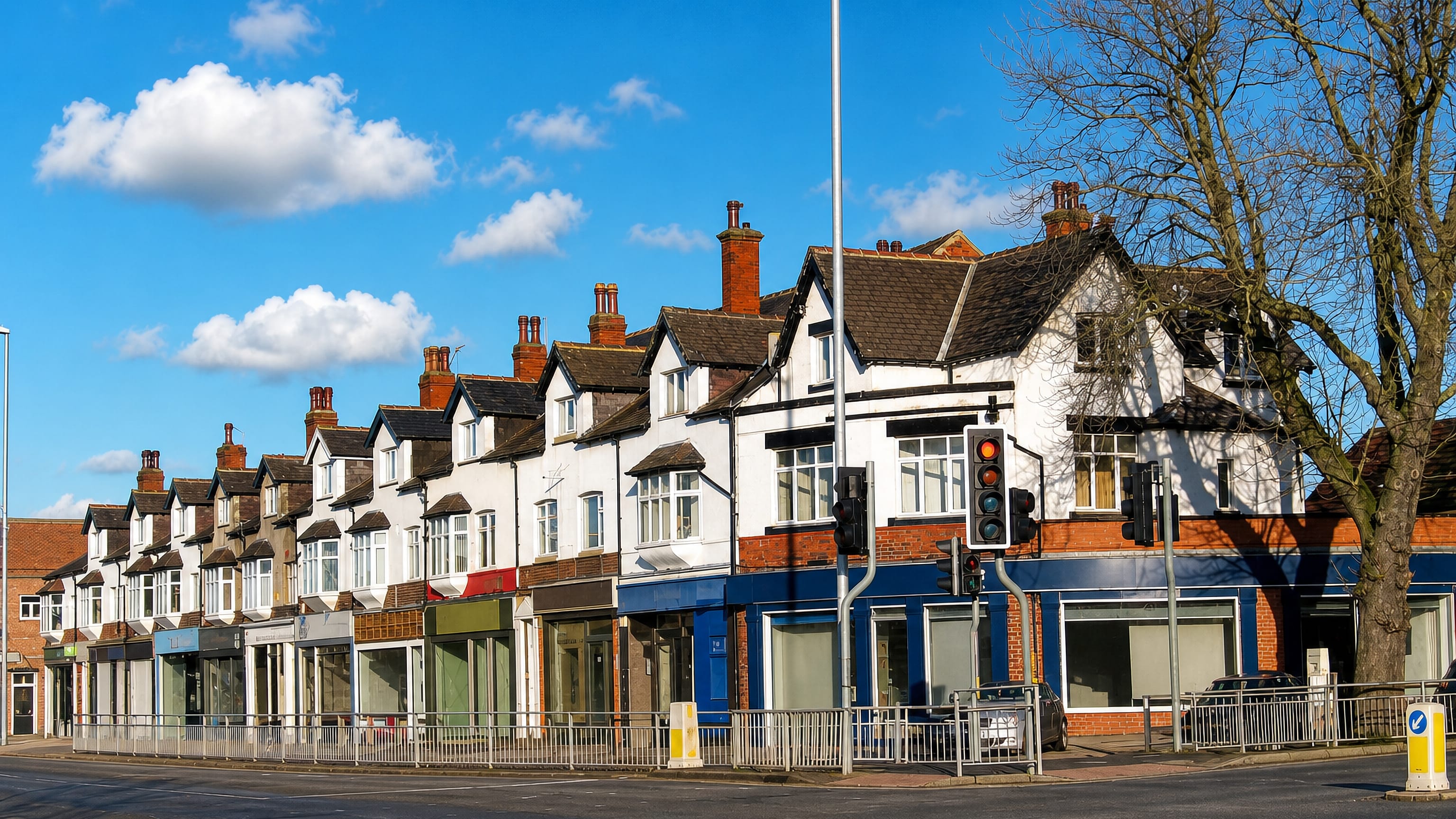 Edwardian mock-Tudor shop parade with brick chimneys along a sunny main road in Moortown, Leeds.