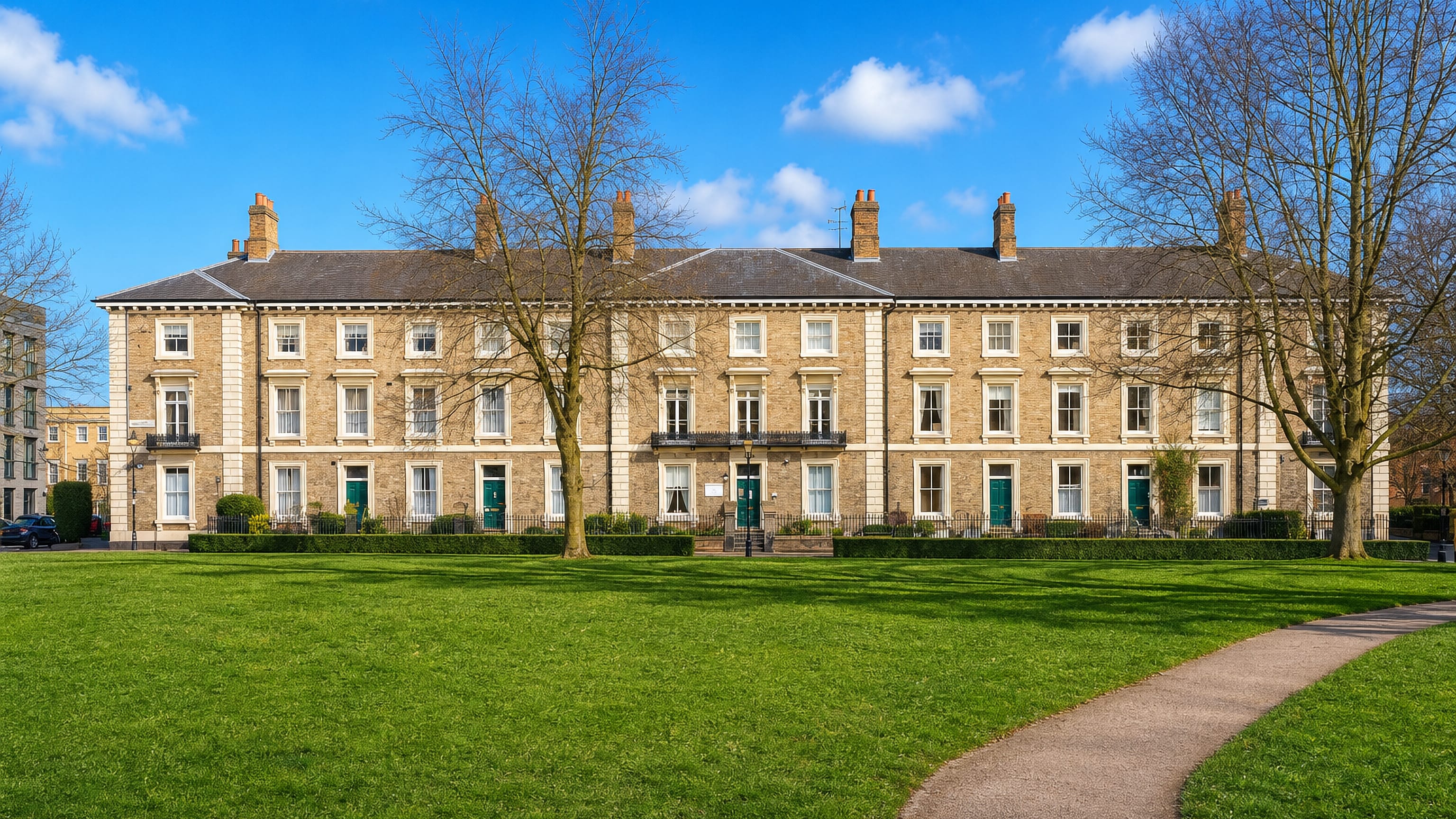 Terrace of pale-brick Georgian houses facing an open green lawn in Highfields, Leicester.