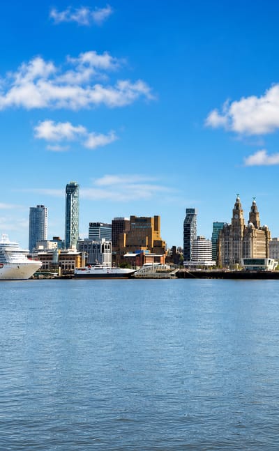 Liverpool's waterfront skyline with the Royal Liver Building and a moored cruise ship across the River Mersey
