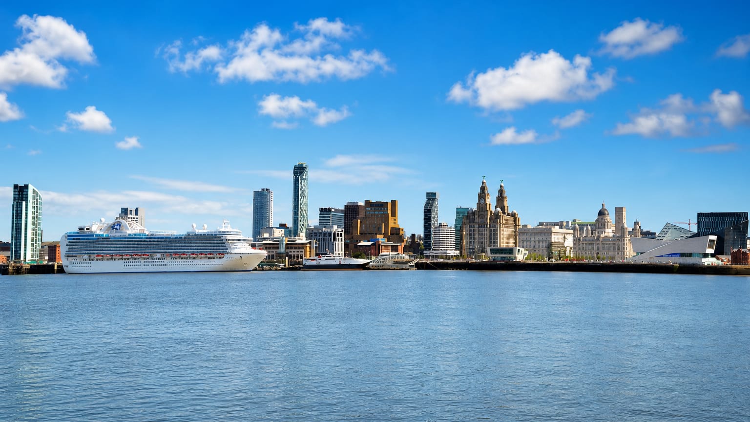 Liverpool's waterfront skyline with the Royal Liver Building and a moored cruise ship across the River Mersey