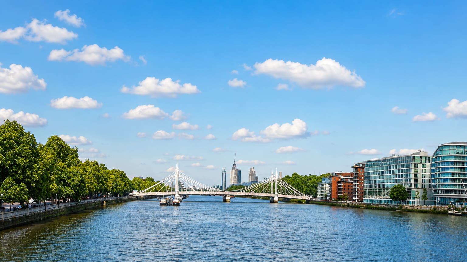 The River Thames at Battersea with a suspension bridge and modern riverside apartment blocks under a blue sky