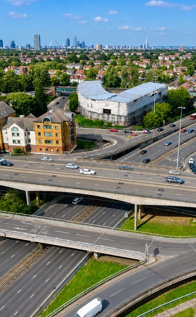 Aerial view of a multi-level road interchange and suburbs with the London skyline beyond, in Brent