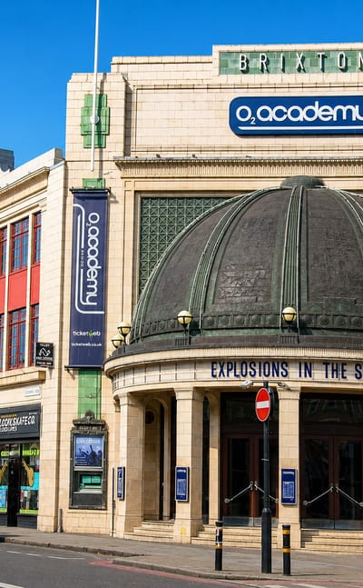 The Art Deco O2 Academy Brixton with its domed entrance and marquee on a sunny Brixton street.