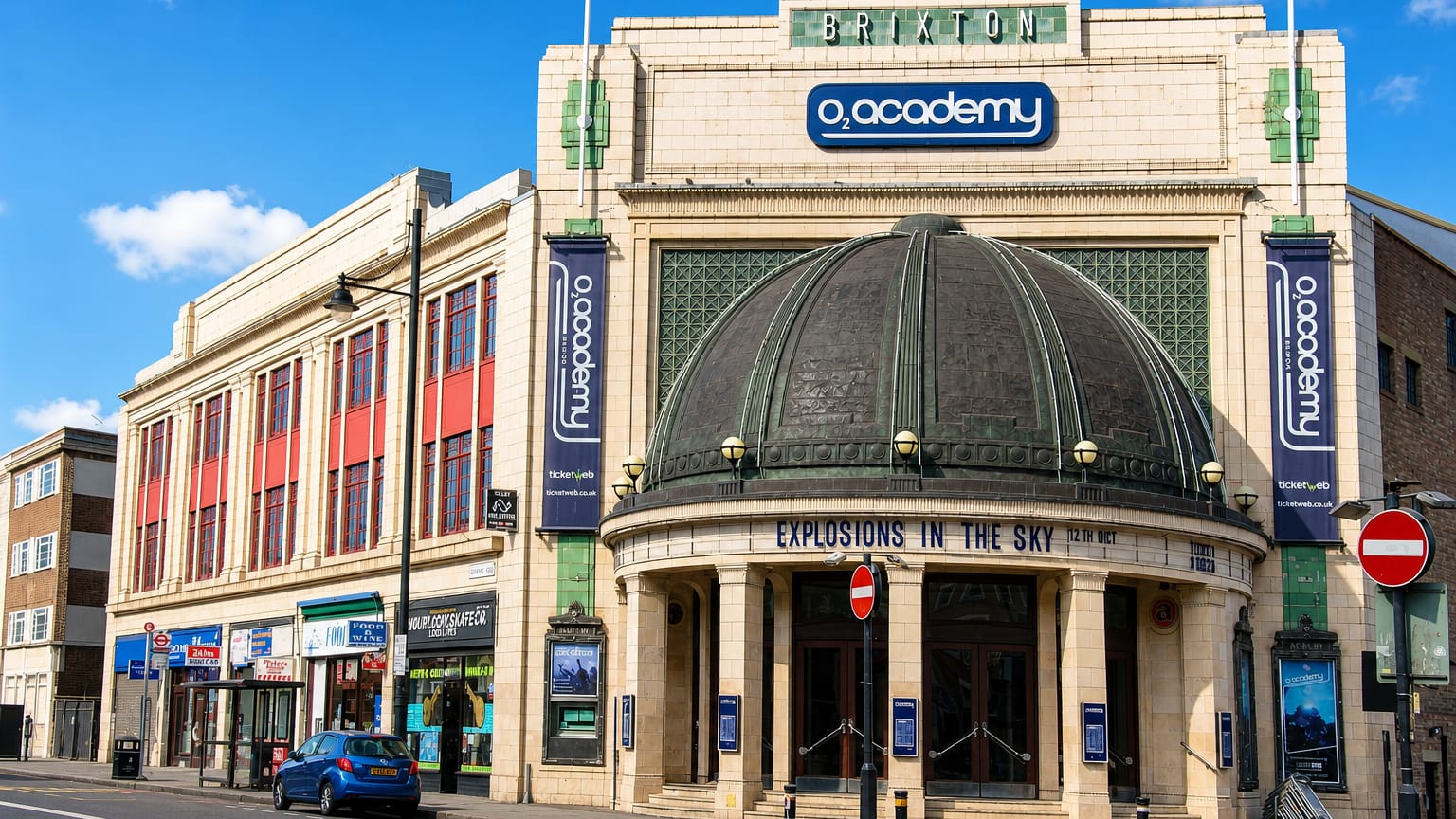 The Art Deco O2 Academy Brixton with its domed entrance and marquee on a sunny Brixton street.
