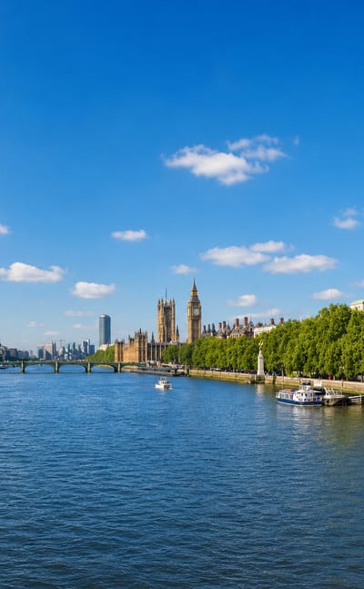 London's River Thames with the London Eye, Big Ben and the Houses of Parliament under a bright blue sky