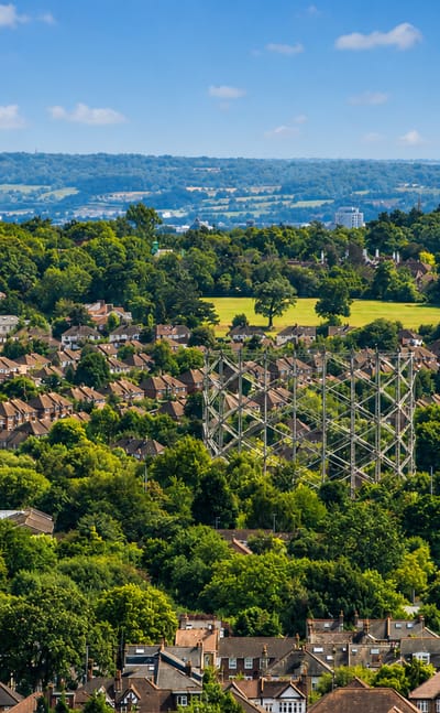 Elevated view over leafy suburban rooftops toward distant wooded hills at High Barnet, North London.