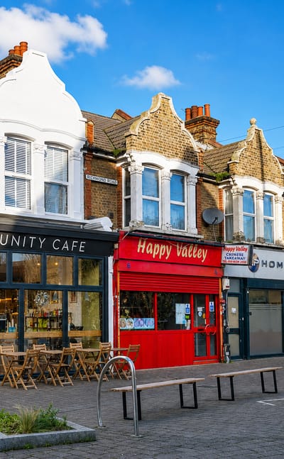 Victorian parade of shops with a cafe and Chinese takeaway on a sunny Leytonstone high street, London.