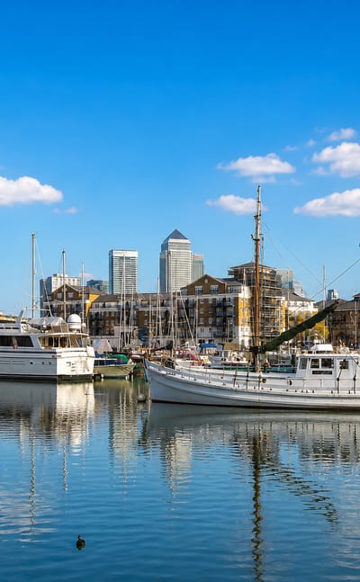 Boats moored in Limehouse Basin with the towers of Canary Wharf rising behind.