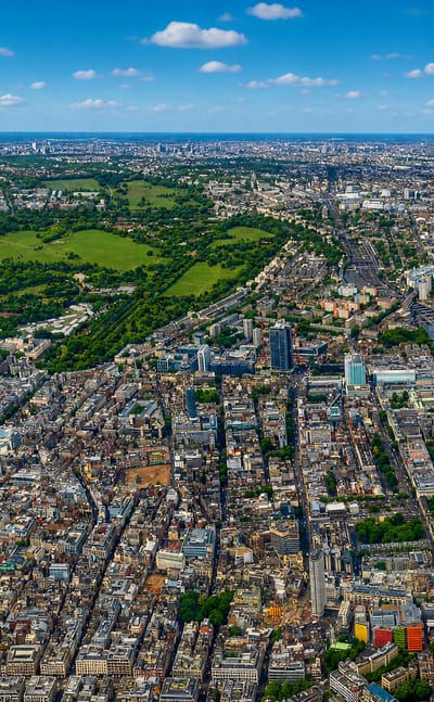 Aerial view over dense central London rooftops with a large green park near Marylebone