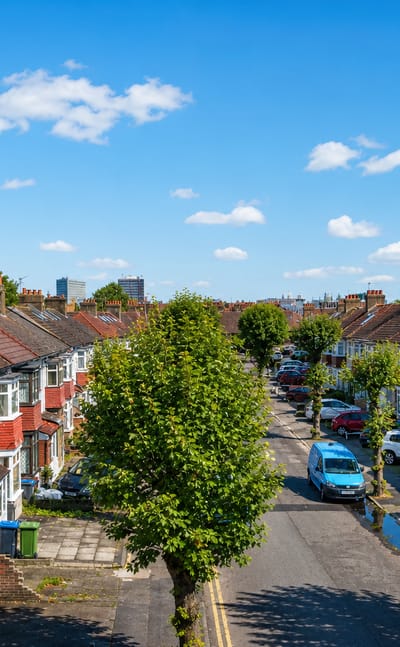 A residential street of terraced houses in New Malden with a distant tower on the skyline.