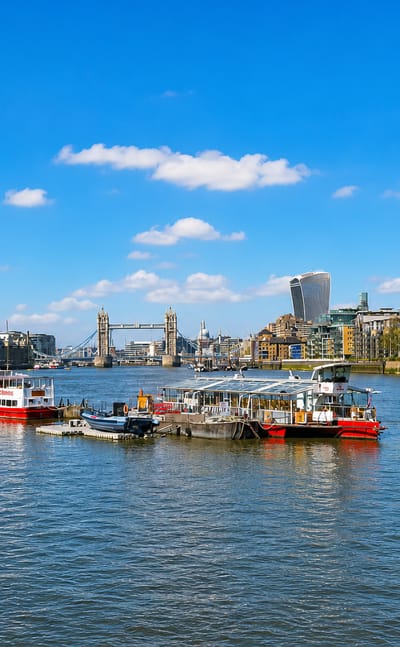 Boats on the Thames off Rotherhithe with Tower Bridge, the Shard and the City of London skyline.
