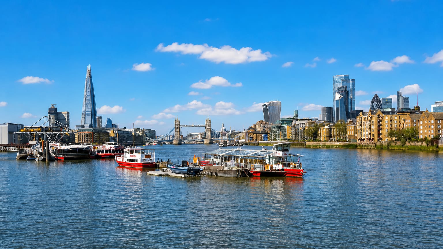 Boats on the Thames off Rotherhithe with Tower Bridge, the Shard and the City of London skyline.