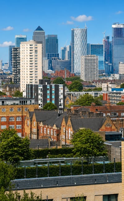 Victorian brick terraces in Whitechapel with the Canary Wharf and City of London towers rising behind.