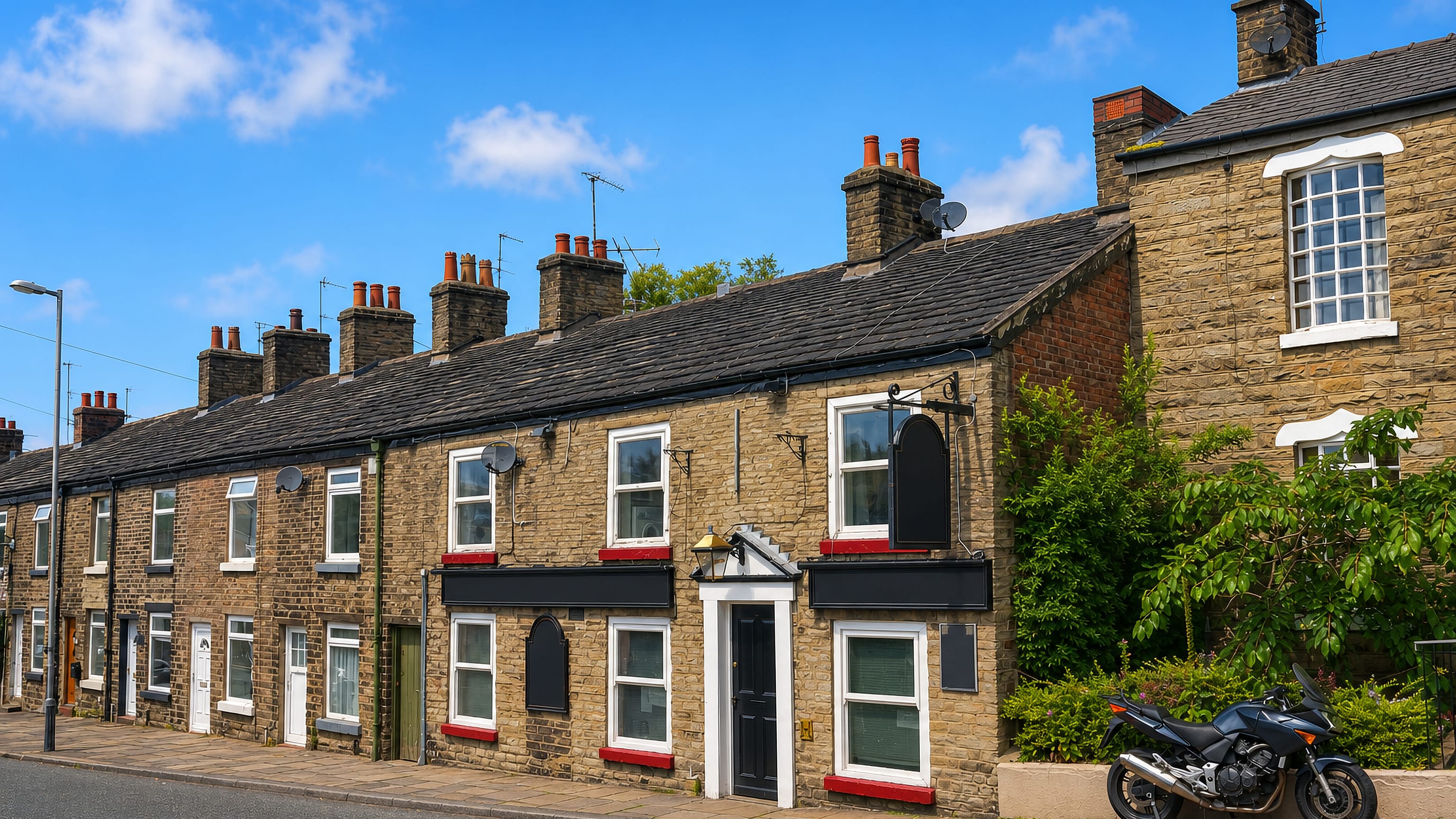 Stone terraced houses and a corner pub on a sloping street in Hurdsfield, Macclesfield, England.
