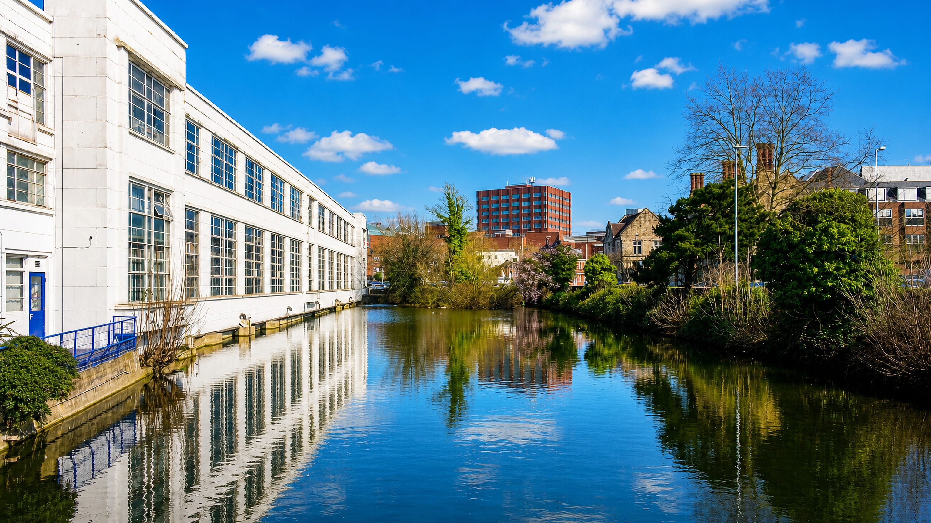 The River Medway in Maidstone, Kent, lined by a white riverside works, ragstone gables and a brick office tower.