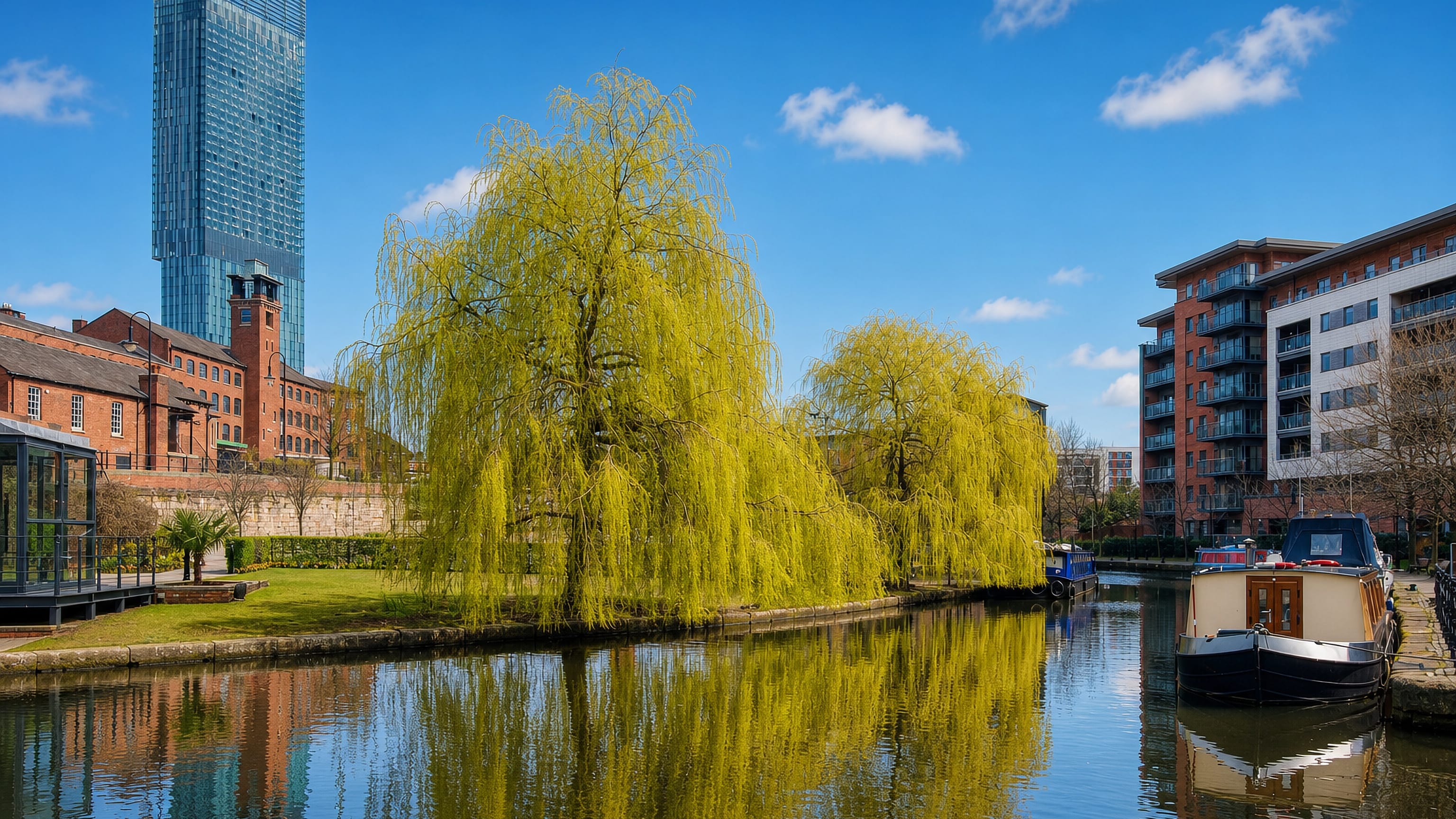Narrowboat on the Castlefield canal basin with willows, brick warehouses and Beetham Tower behind, Manchester.