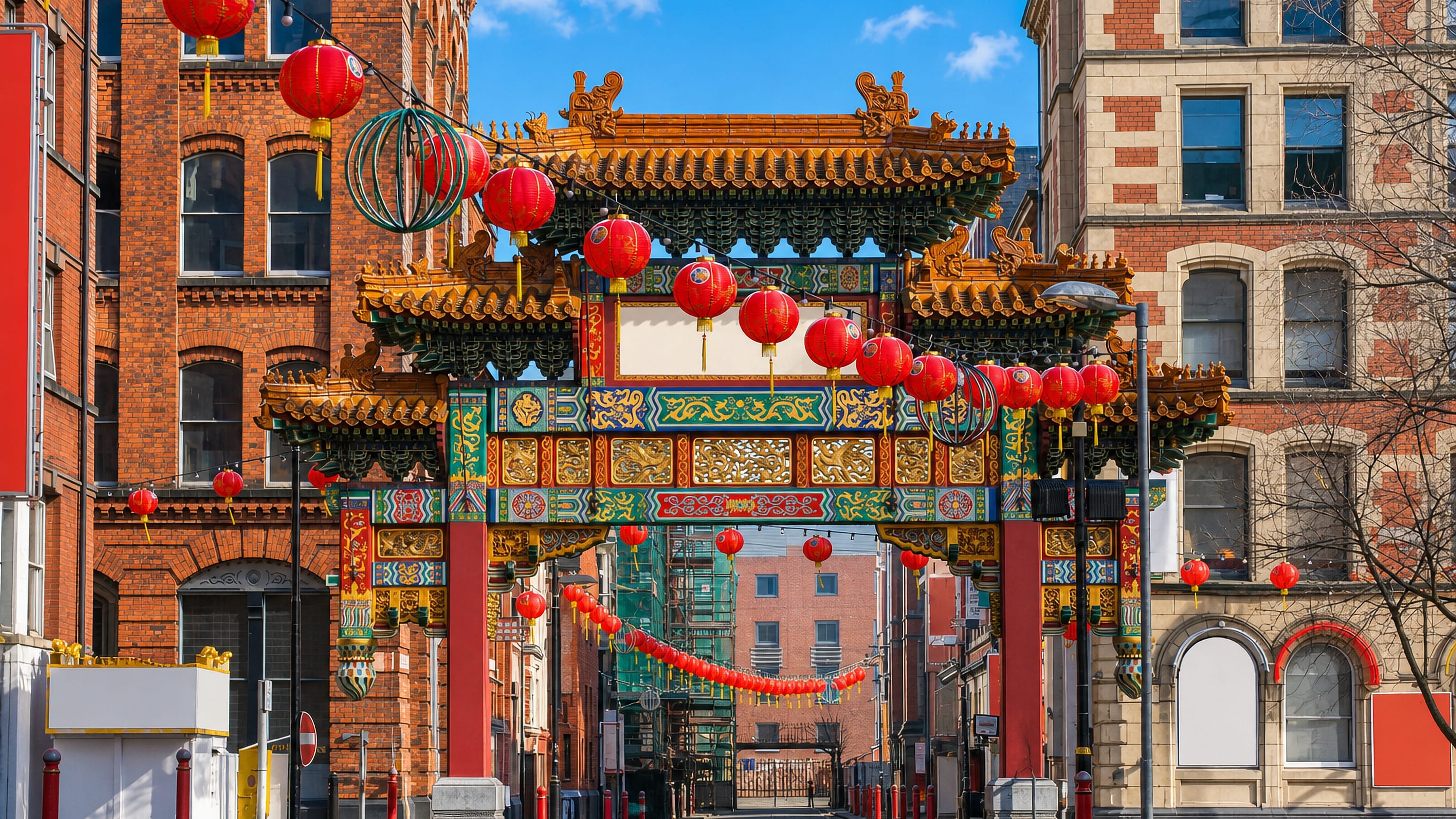 Manchester Chinatown's ornate paifang arch hung with red lanterns between Victorian red-brick buildings