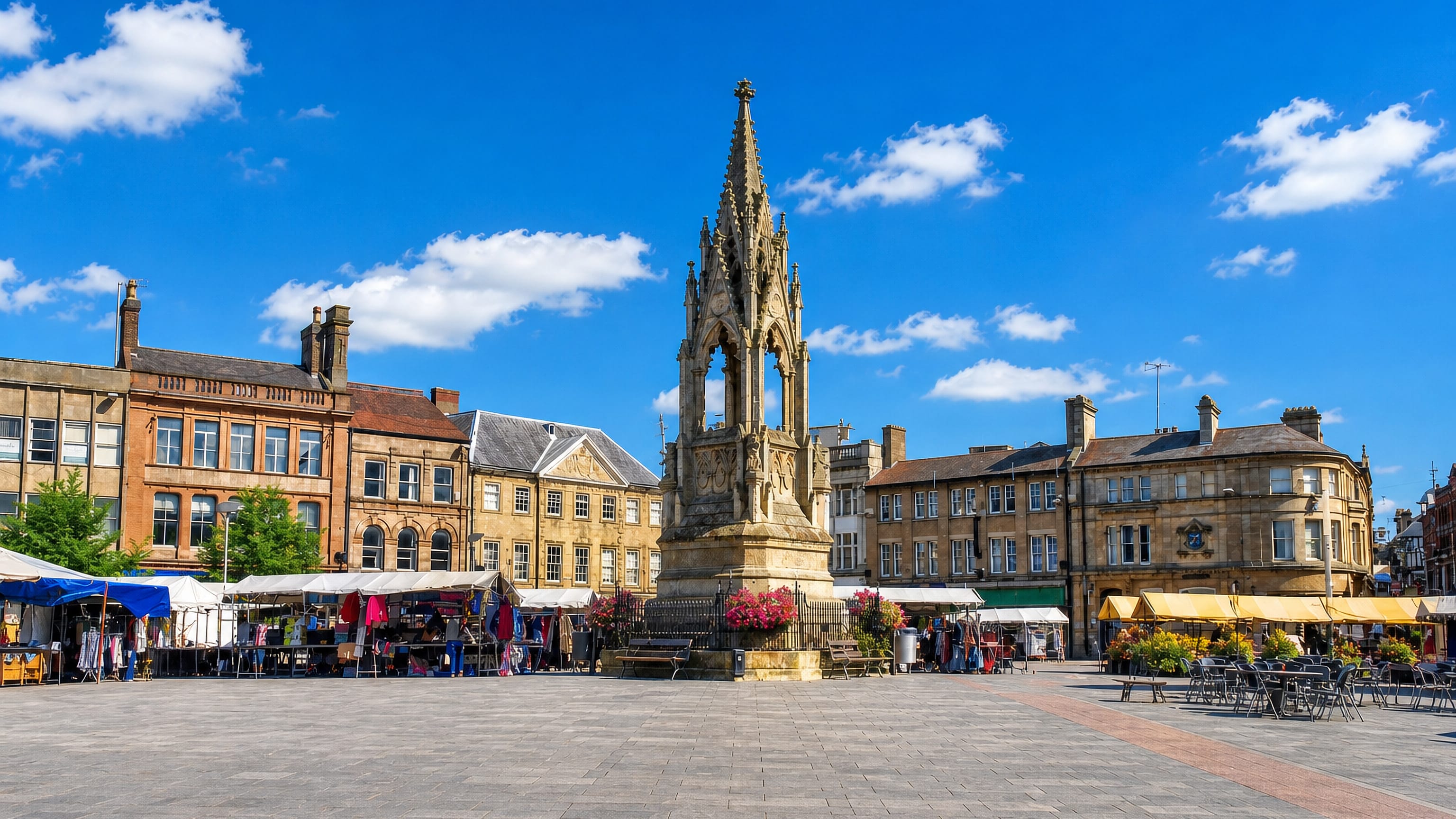 Mansfield Market Place with the Gothic Bentinck Memorial, market stalls and Georgian frontages.