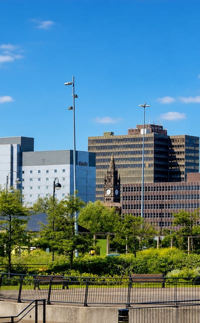 Middlesbrough town-centre skyline of office blocks and a clock tower seen across a landscaped park.