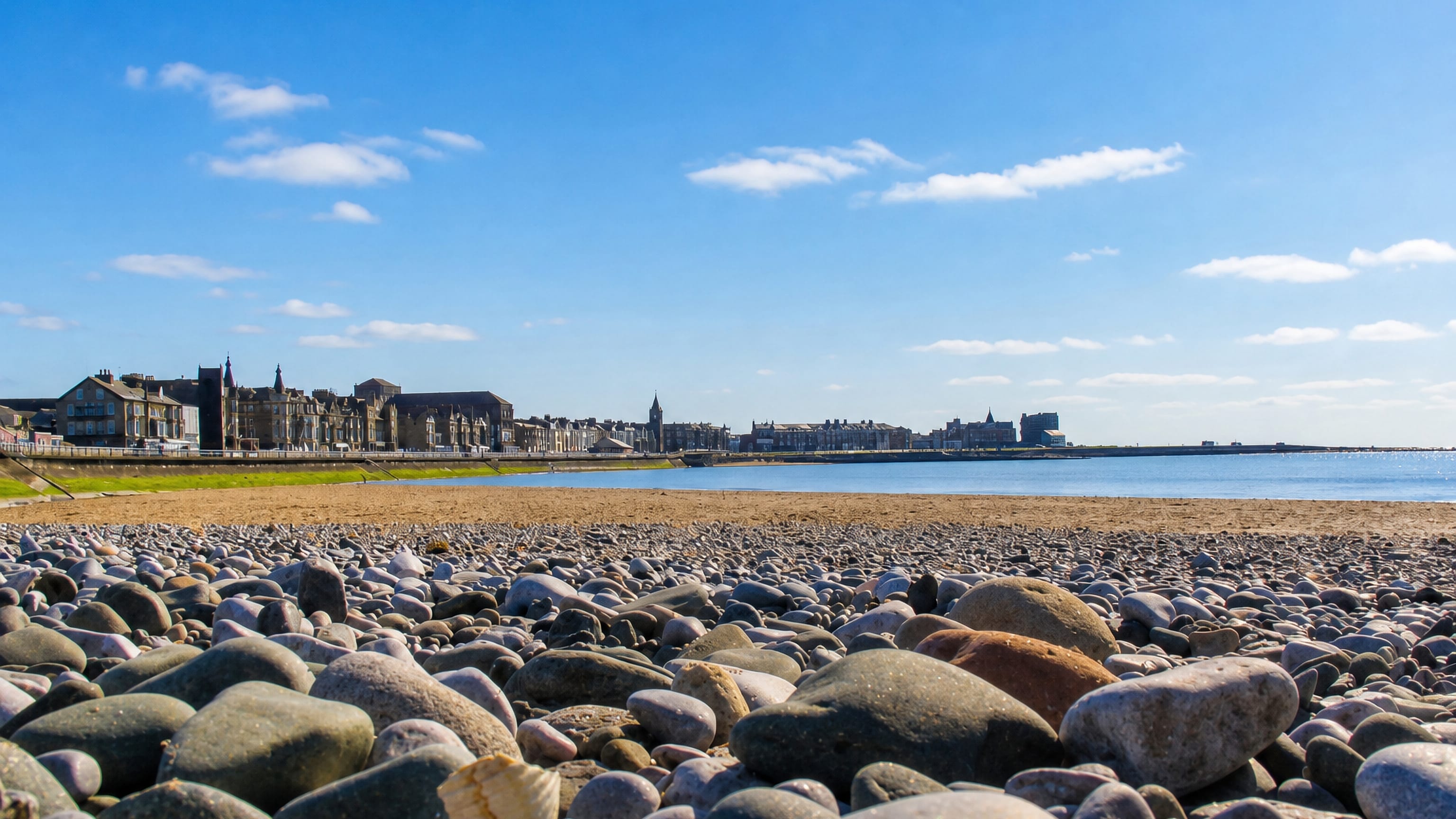 Morecambe's Victorian seafront terraces seen across the pebble and sand beach of Morecambe Bay, England