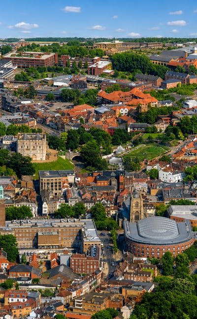 Aerial view of Norwich with its Norman castle keep among the historic city rooftops.