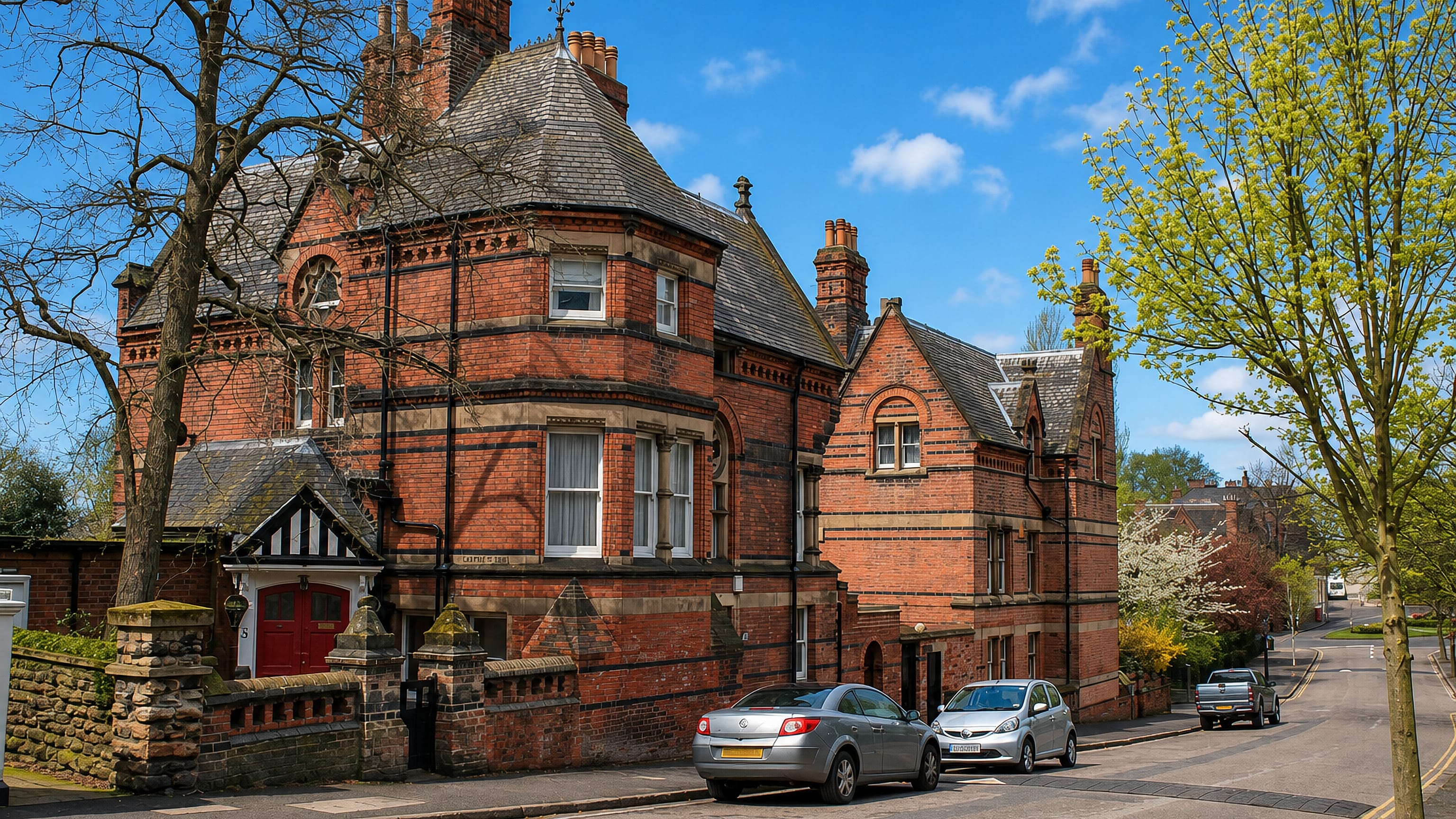 Victorian red-brick villa with turret and stone garden wall on a curving street in The Park estate, Nottingham.