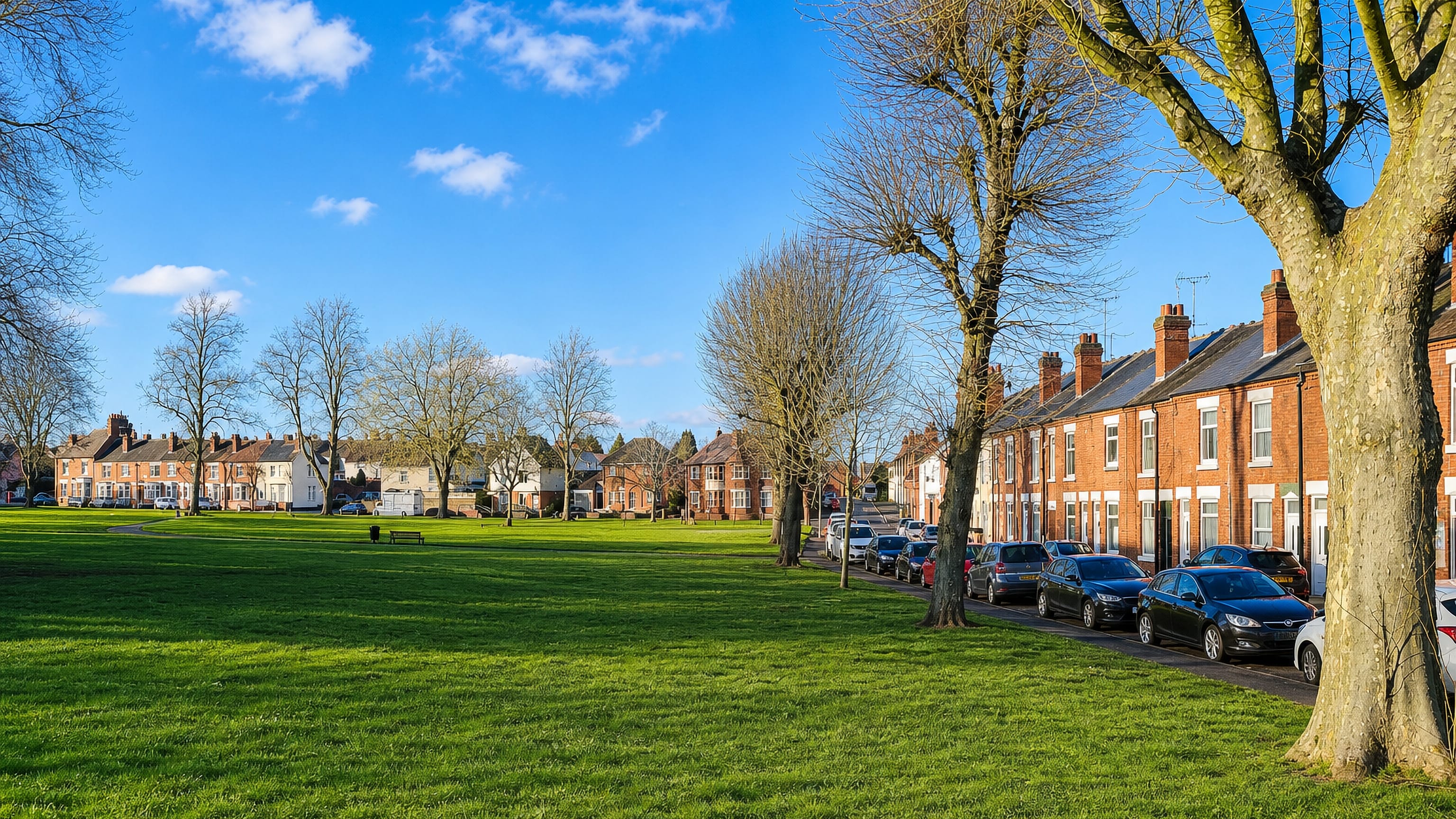 Wide green common lined with red-brick Victorian terraces and bare trees in Nuneaton, England.
