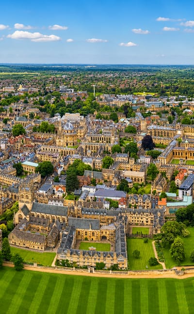 Aerial view of Oxford's historic college quadrangles and spires beside Christ Church Meadow