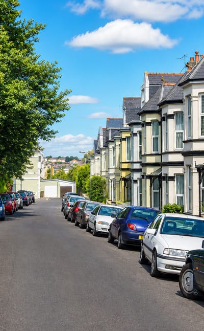 Sloping street of bay-windowed Edwardian terraces with parked cars in Hartley, Plymouth.