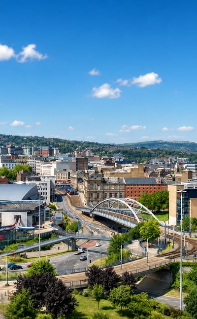 Sheffield city centre in daylight with the arched Park Square tram bridge, tram lines and green hills behind.