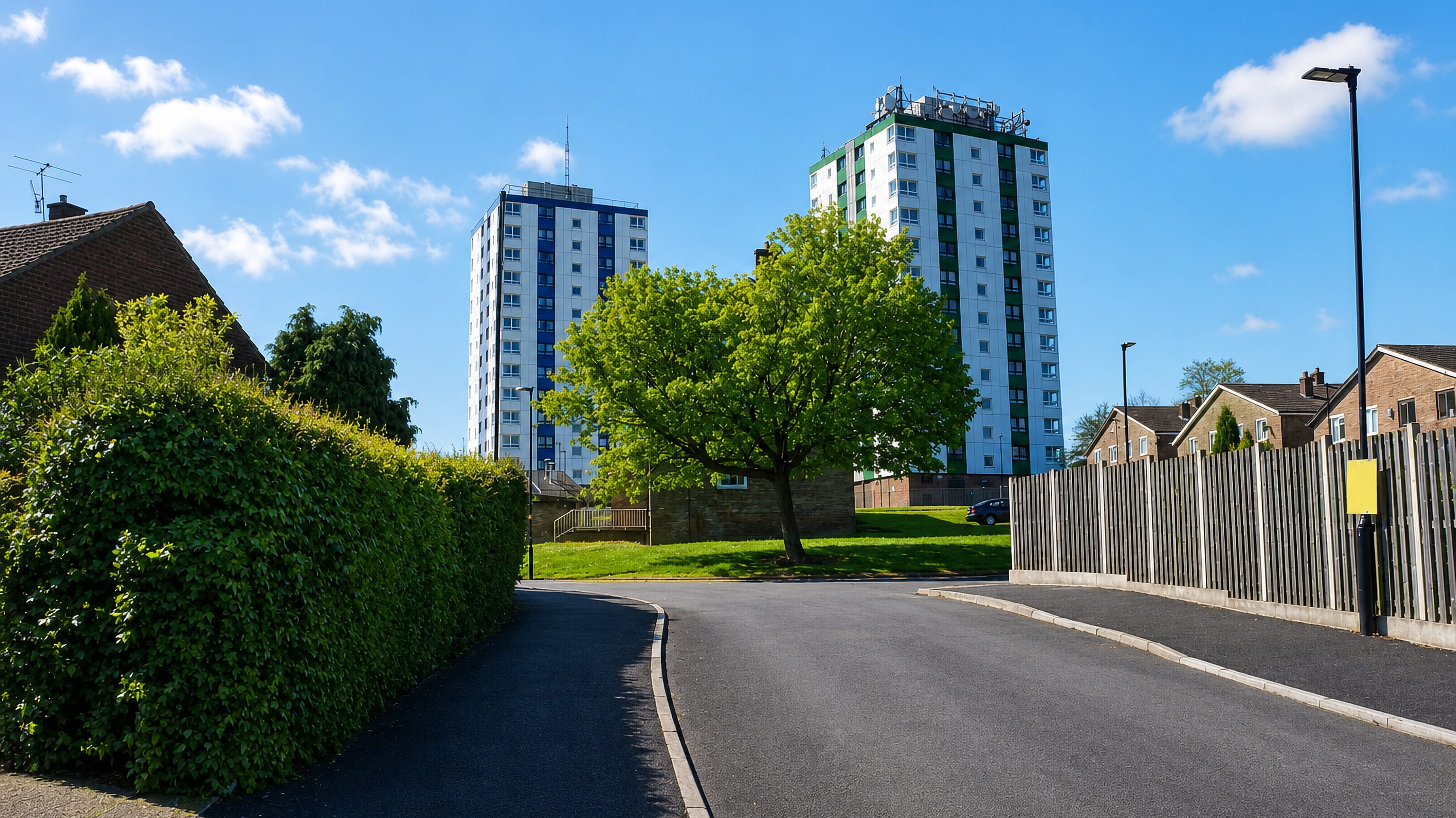The blue and green Herdings tower blocks rising above a quiet suburban street in Herdings, Sheffield.