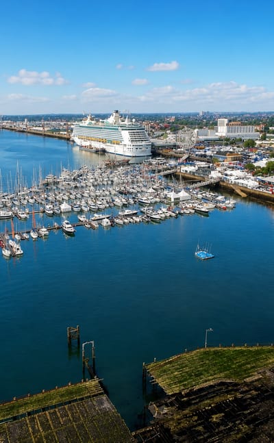 Southampton's waterfront with a moored cruise ship, yacht marina and dockside buildings under a blue sky